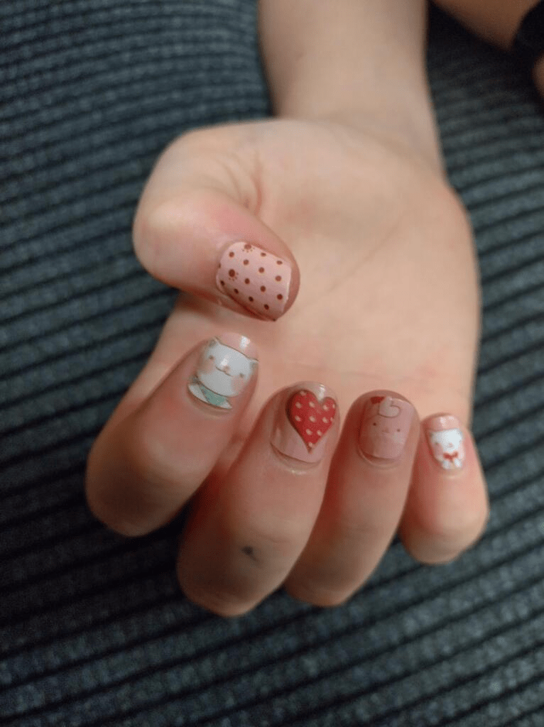 Kids' nail wraps in nude tones with polka dots, cat faces, and red heart designs