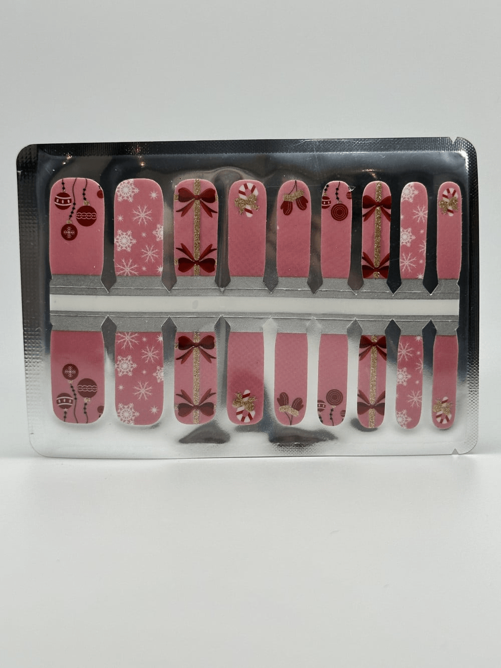 Pink kids nail wraps with Christmas candy canes and bow patterns in packaging