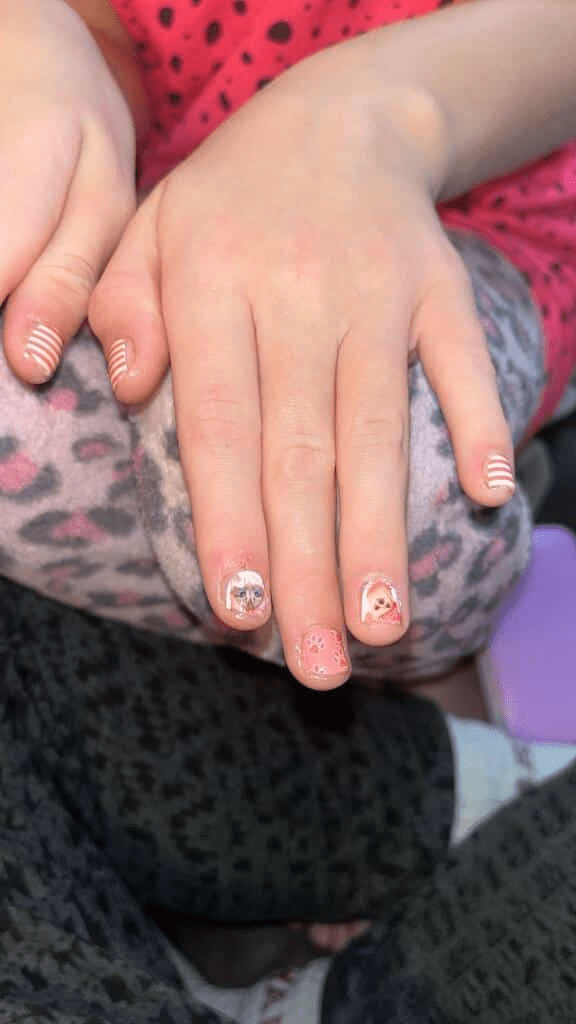Child's hands showing cat and dog pattern kids nail wraps with white striped accent nails