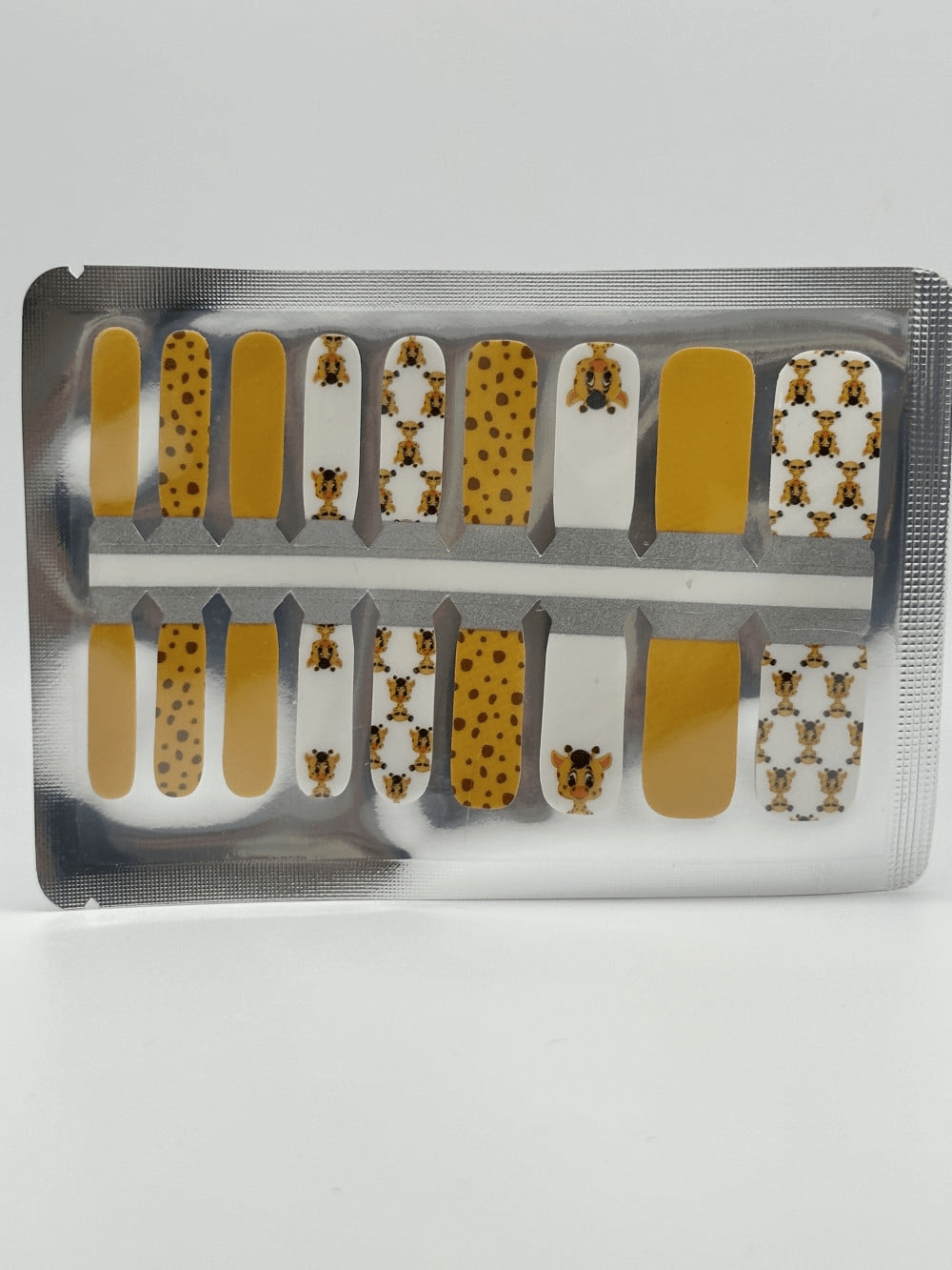 Kids nail wraps featuring yellow giraffe spots and brown patterns in sealed packaging