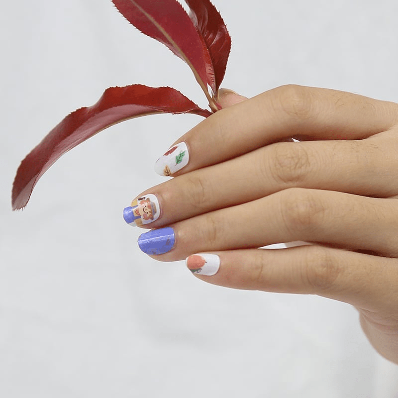 Children's nail wraps on hand with blue and autumn pumpkin character nail art