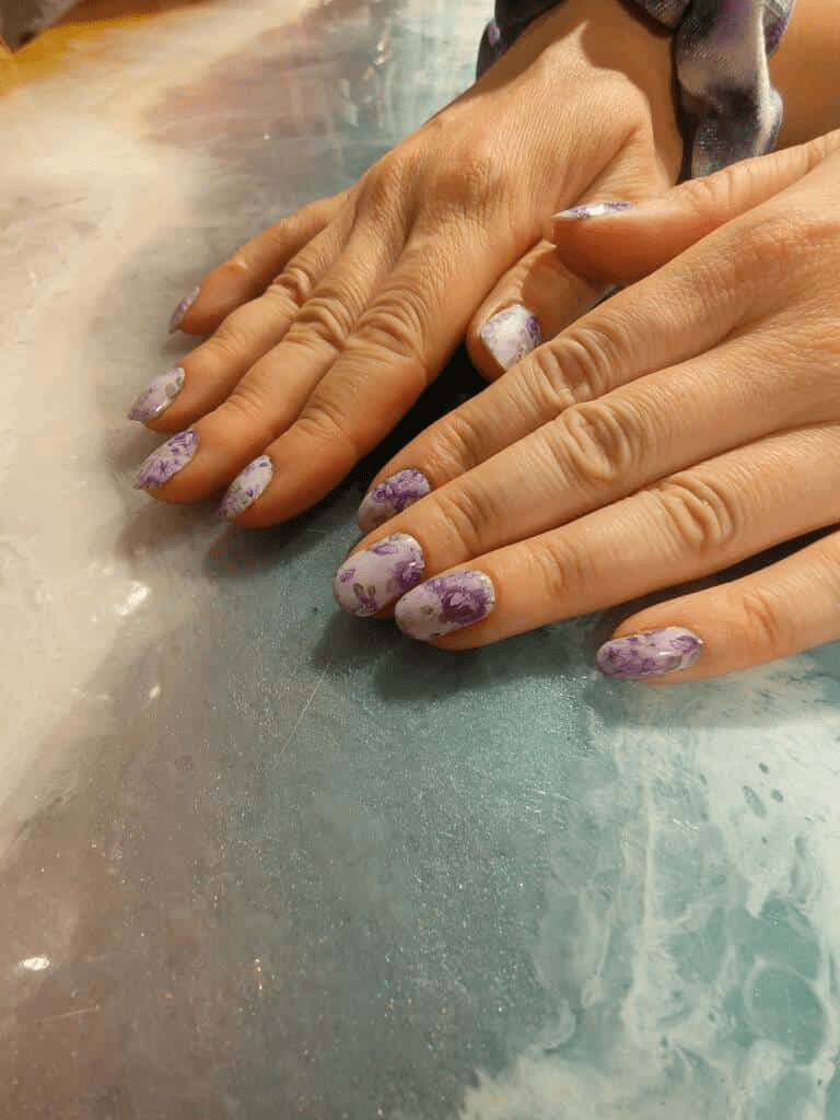 Both hands showing purple floral nail wraps with rose pattern design