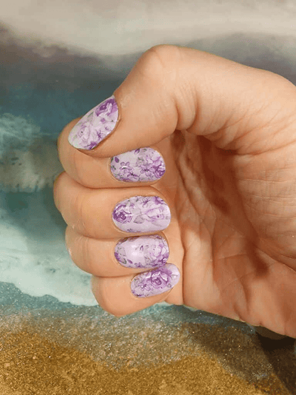 Purple floral nail wraps on hand showing rose pattern manicure design