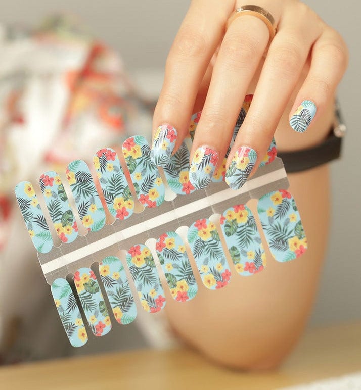 Tropical blue palm leaf and hibiscus flower nail wraps on hand displaying colourful summer nail art