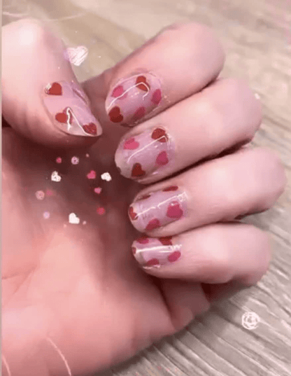 Pink heart pattern nail wraps on hand showing Valentine's Day nail art design