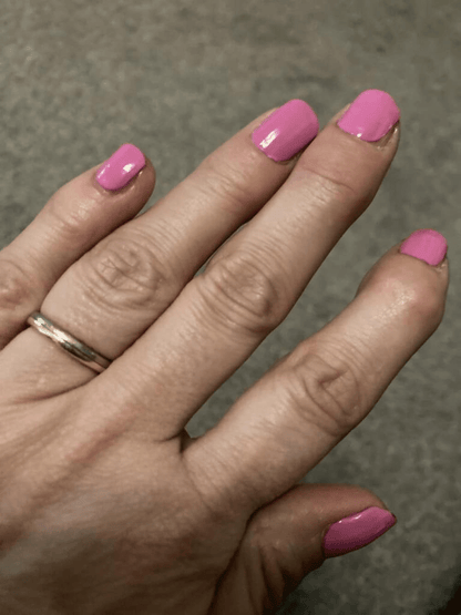 Hand displaying bright pink glossy nail wraps in vibrant hot pink finish for at-home manicure