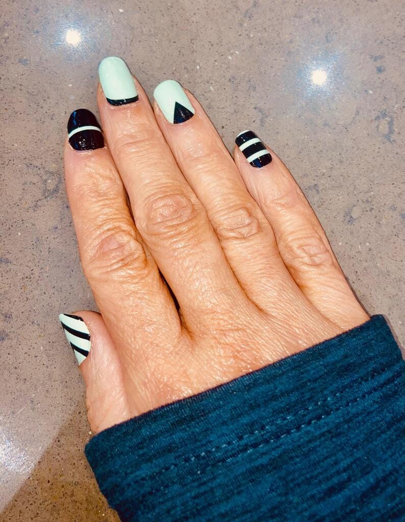 Hands displaying mint green black striped geometric nail art wraps manicure