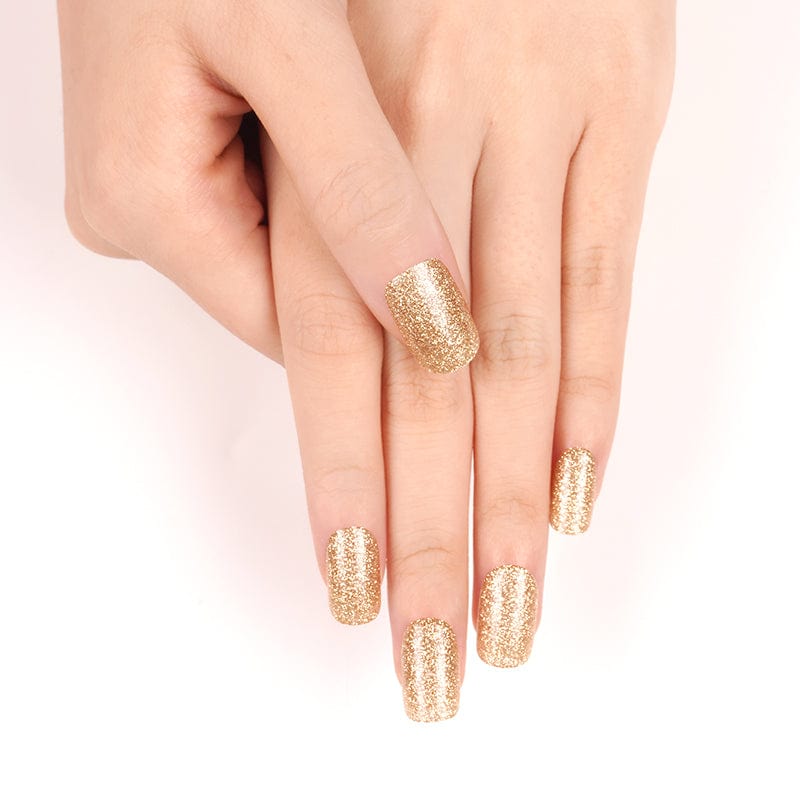 Gold glitter nail wraps on hands showing sparkly at-home manicure finish