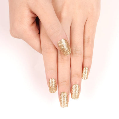 Gold glitter nail wraps on hands showing sparkly at-home manicure finish