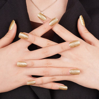 Hands displaying gold glitter nail wraps with sparkly finish for glamorous nail art