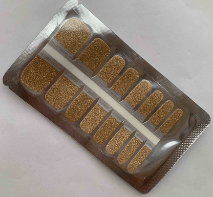 Golden glitter pedicure nail wraps in packaging showing sparkly metallic strips for toes