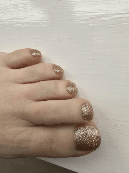 Foot wearing gold glitter pedicure nail wraps on toes for sparkly nail art