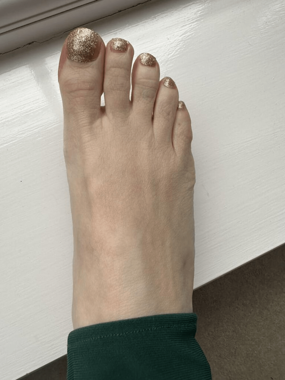 Golden glitter pedicure wraps on toes showing sparkly metallic finish for festive nail art