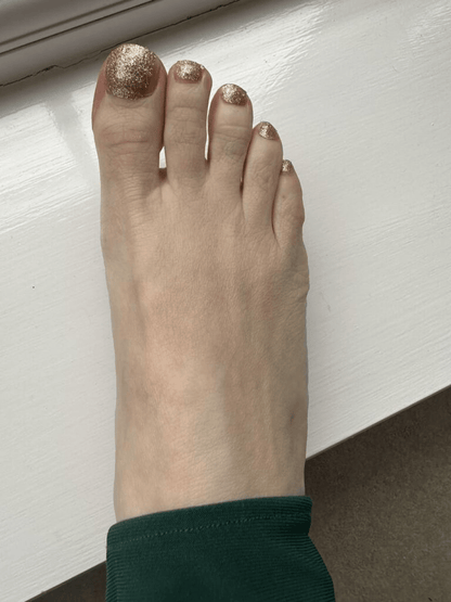 Golden glitter pedicure wraps on toes showing sparkly metallic finish for festive nail art