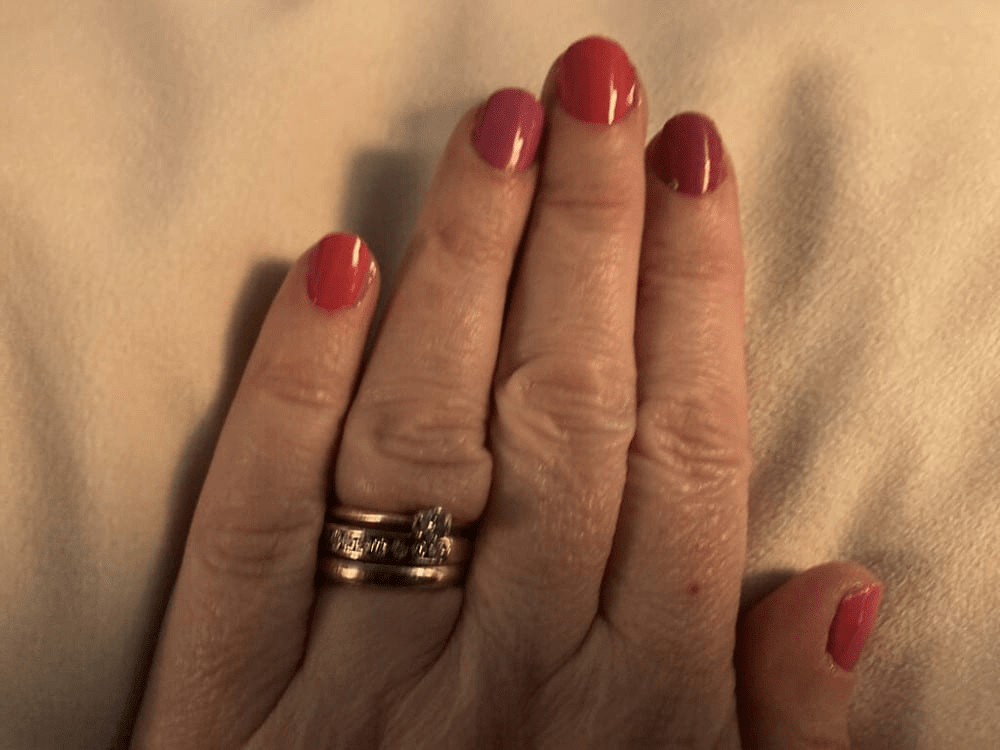 Deep red glossy nail wraps on hand showing berry manicure with gold ring