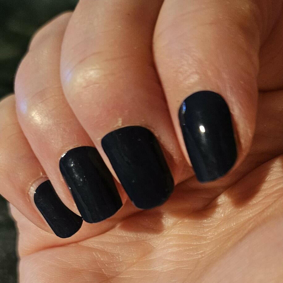 Black semi-matte nail wraps in a solid, near-black shade shown on short, wide-fit nails.