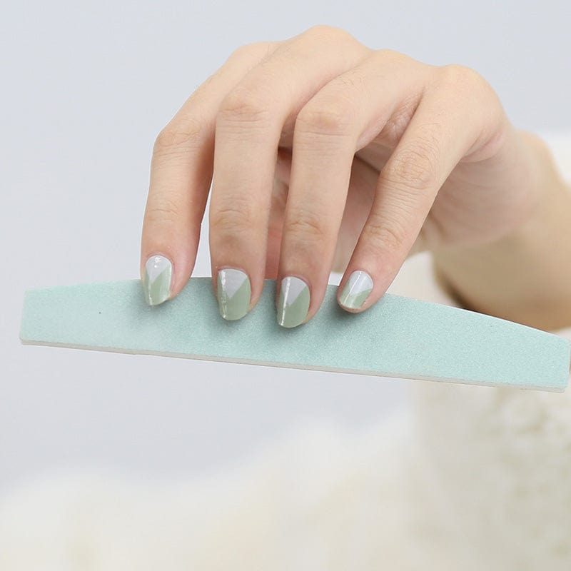 Sage green nail wraps on fingertips touching mint green surface