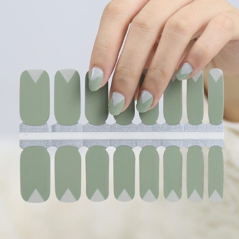 Hand wearing sage green chevron nail wraps with white mountain pattern nail art