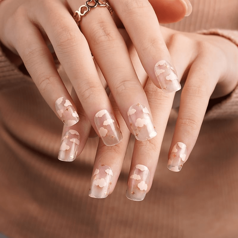 Pink cloud nail art wraps with stars on hand showing dreamy at-home manicure design