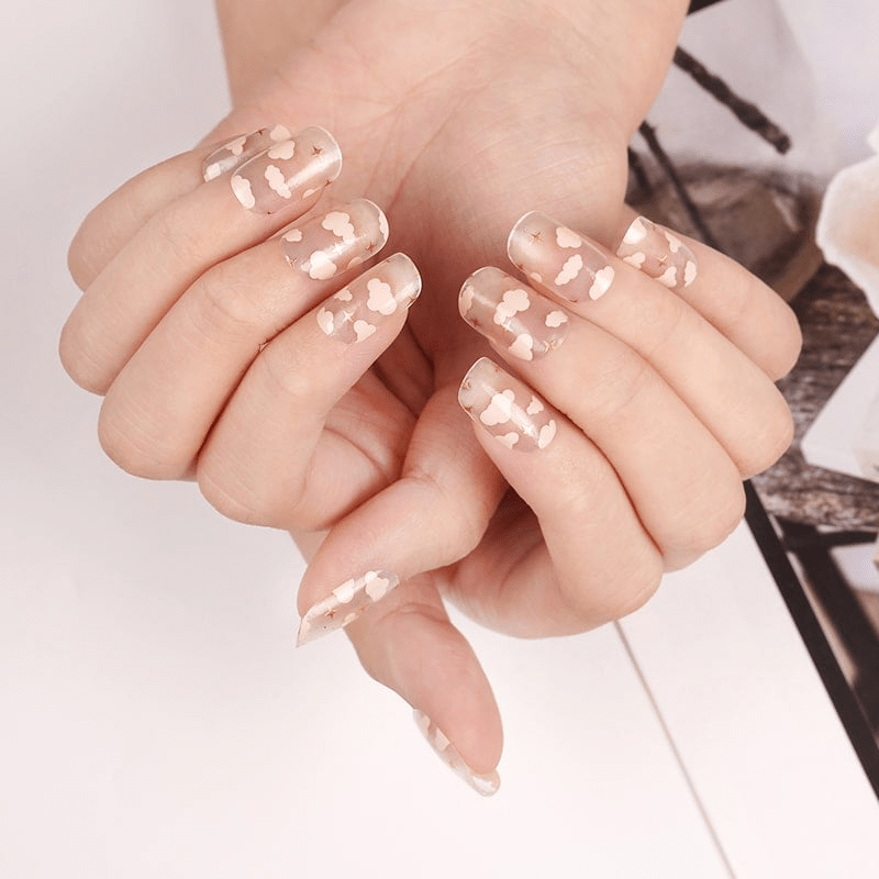 Transparent pink cloud pattern nail wraps on hands creating celestial nail art design