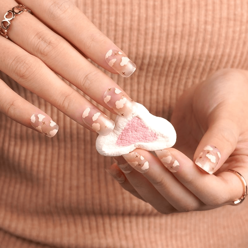 Hand wearing pink cloud pattern nail wraps with transparent background for dreamy manicure