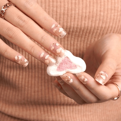 Hand wearing pink cloud pattern nail wraps with transparent background for dreamy manicure