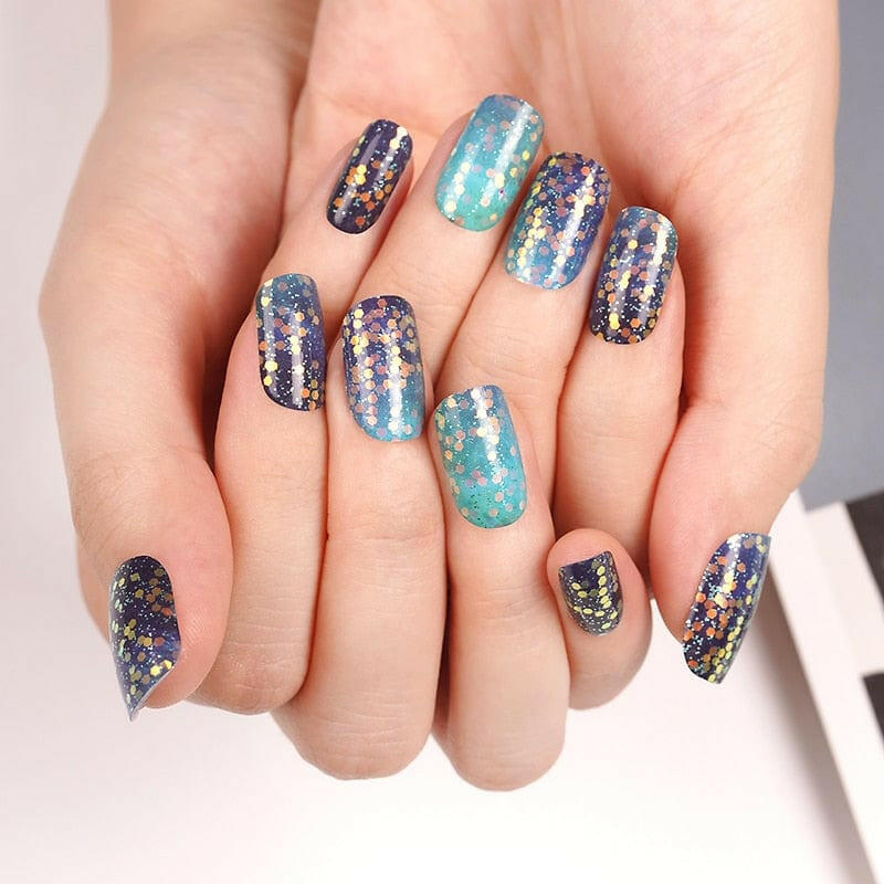Blue teal ombre glitter nail wraps on hand showing sparkly gradient manicure design