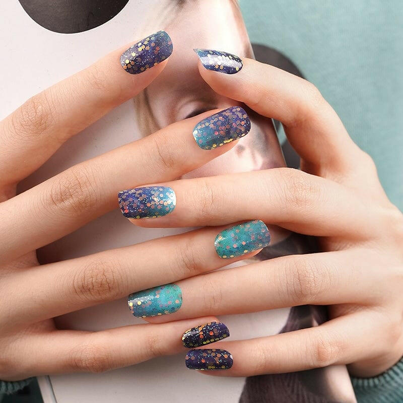 Hands displaying blue to teal glitter ombre nail wraps with sparkly gradient finish