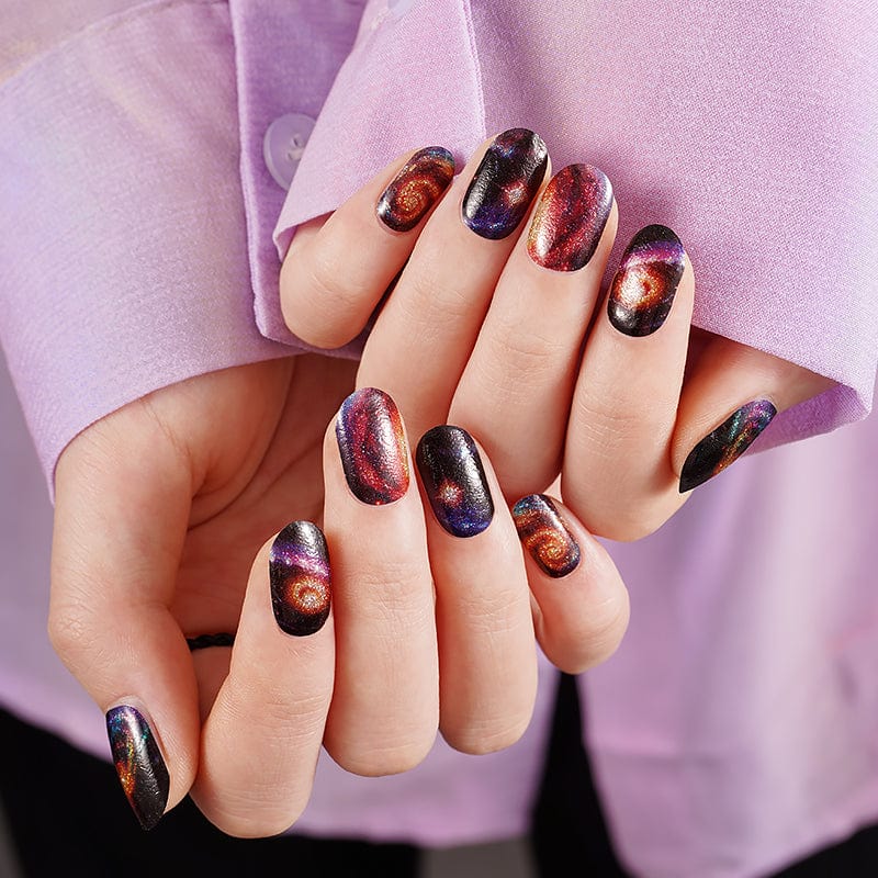 Galaxy space pattern nail wraps on hands showing cosmic nebula design in purple blue orange