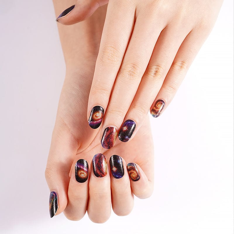Two hands showing cosmic galaxy nail art with purple orange space patterns