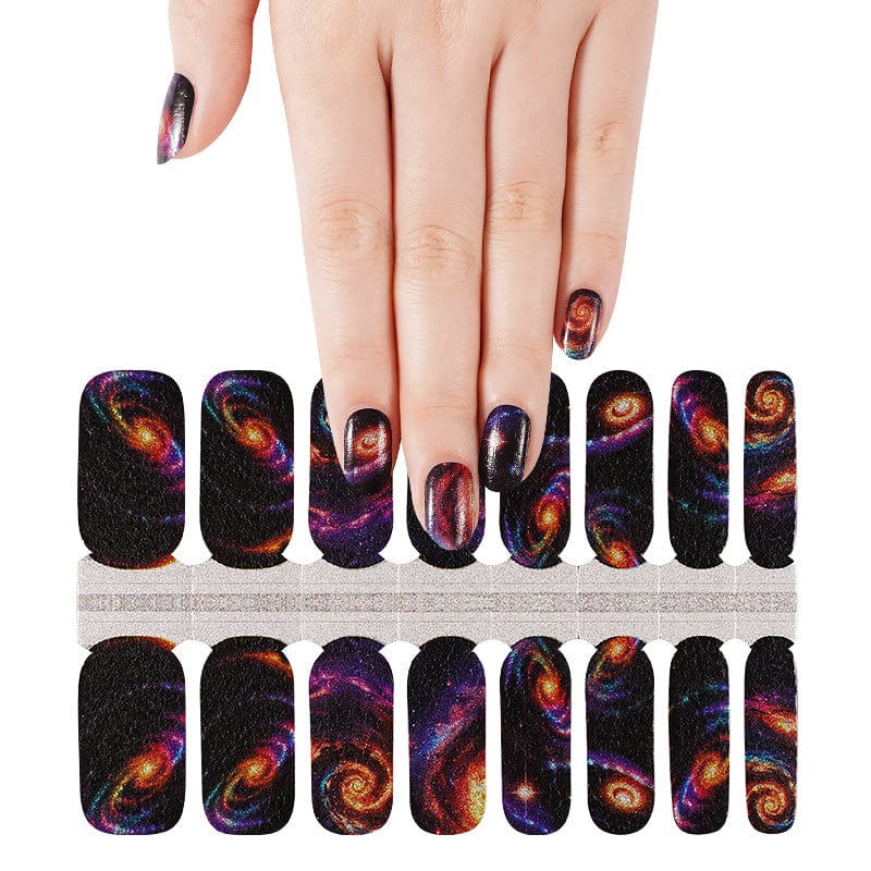 Hand displaying space galaxy nail wraps with cosmic nebula designs sheet below