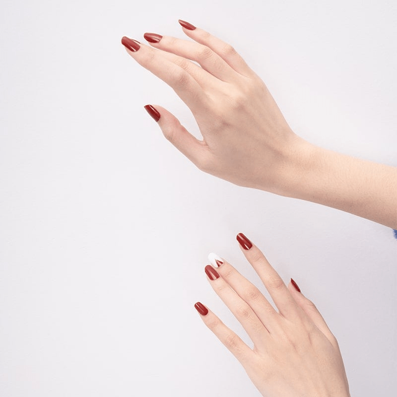 Two hands displaying red matte geometric nail art wraps against white background