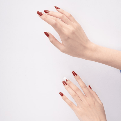 Two hands displaying red matte geometric nail art wraps against white background