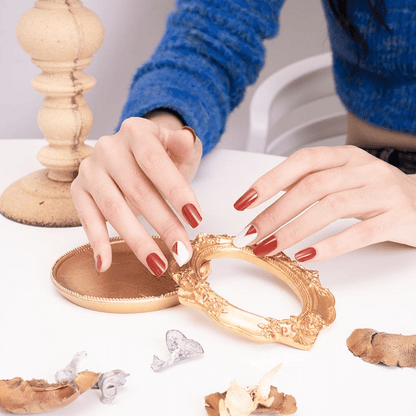 Hands with red matte geometric nail wraps styling vintage gold mirror