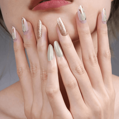 Manicured hands showcasing gold glitter and marble nail wraps with abstract designs