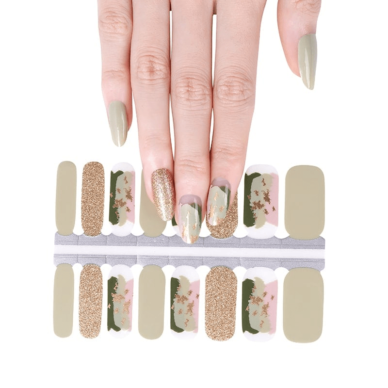 Hand displaying sage green floral nail wraps with gold glitter and pink flower patterns
