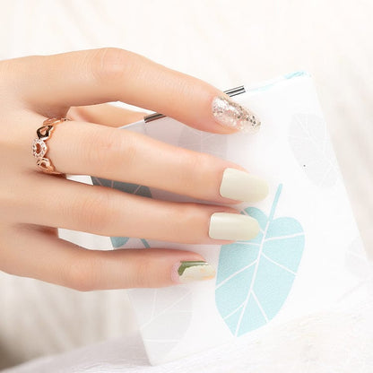 Pale sage green nail wraps with gold glitter accent and abstract marbled tip design