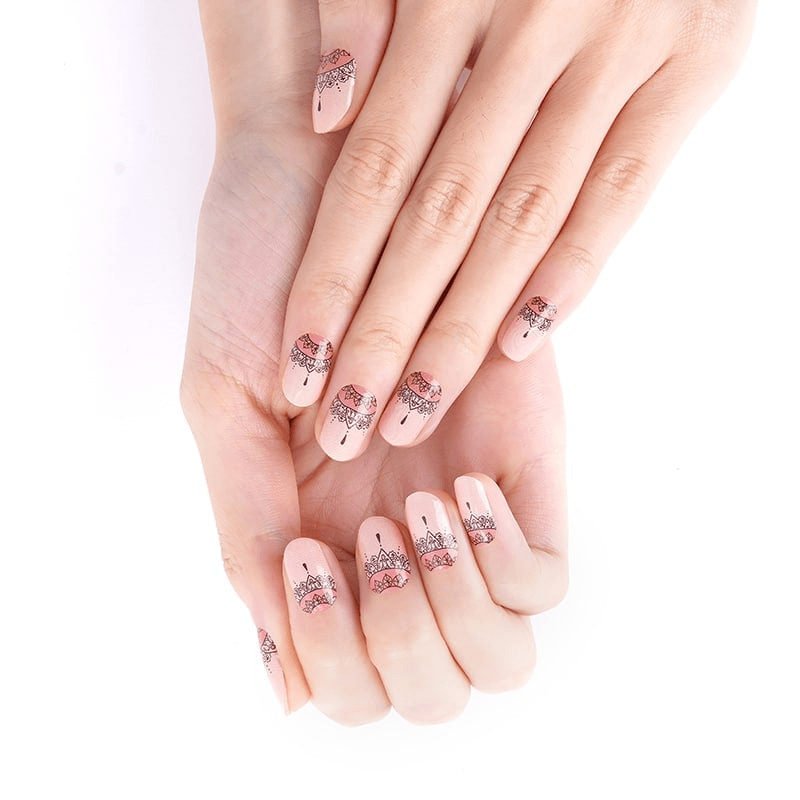 Hands wearing peach nail wraps with black lace Aztec sunset pattern design