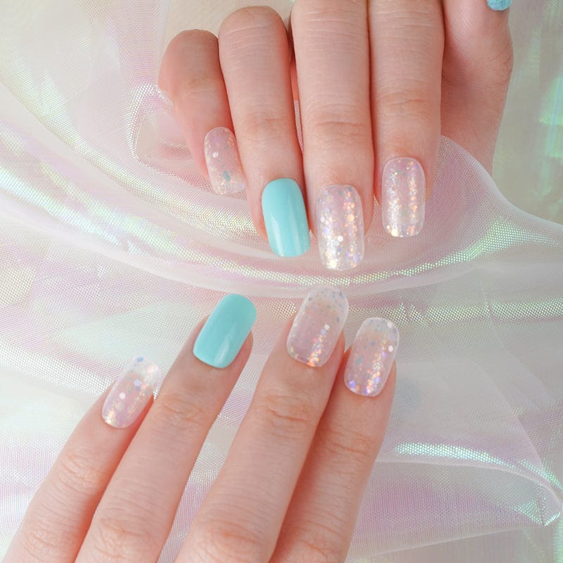 Two hands displaying turquoise and clear glitter nail wraps with sparkly ice-effect manicure design