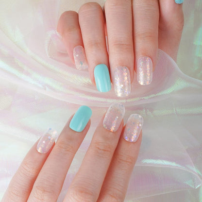 Two hands displaying turquoise and clear glitter nail wraps with sparkly ice-effect manicure design