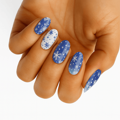 Blue winter nail wraps with white snowflakes on hand showing festive manicure design