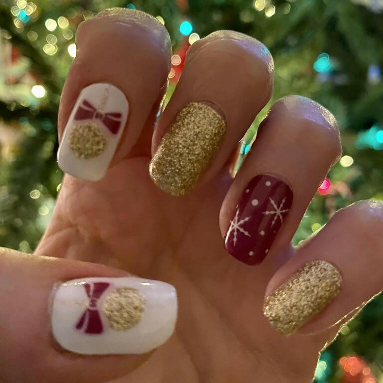 Festive Christmas nail art with burgundy and gold glitter nail wraps on hand
