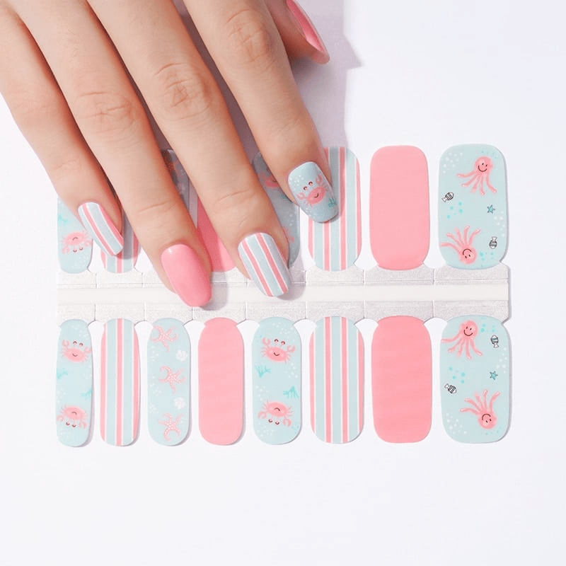 Hand wearing pink and blue striped nail wraps with cute sea creature designs