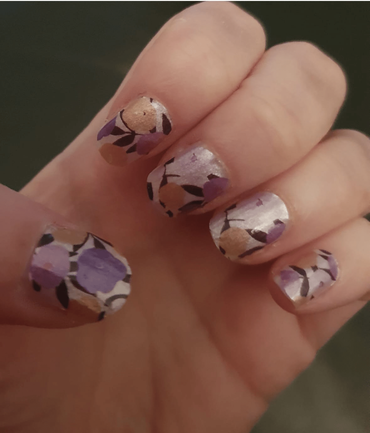 Hand showing purple floral nail wraps with yellow flowers on glossy finish nails