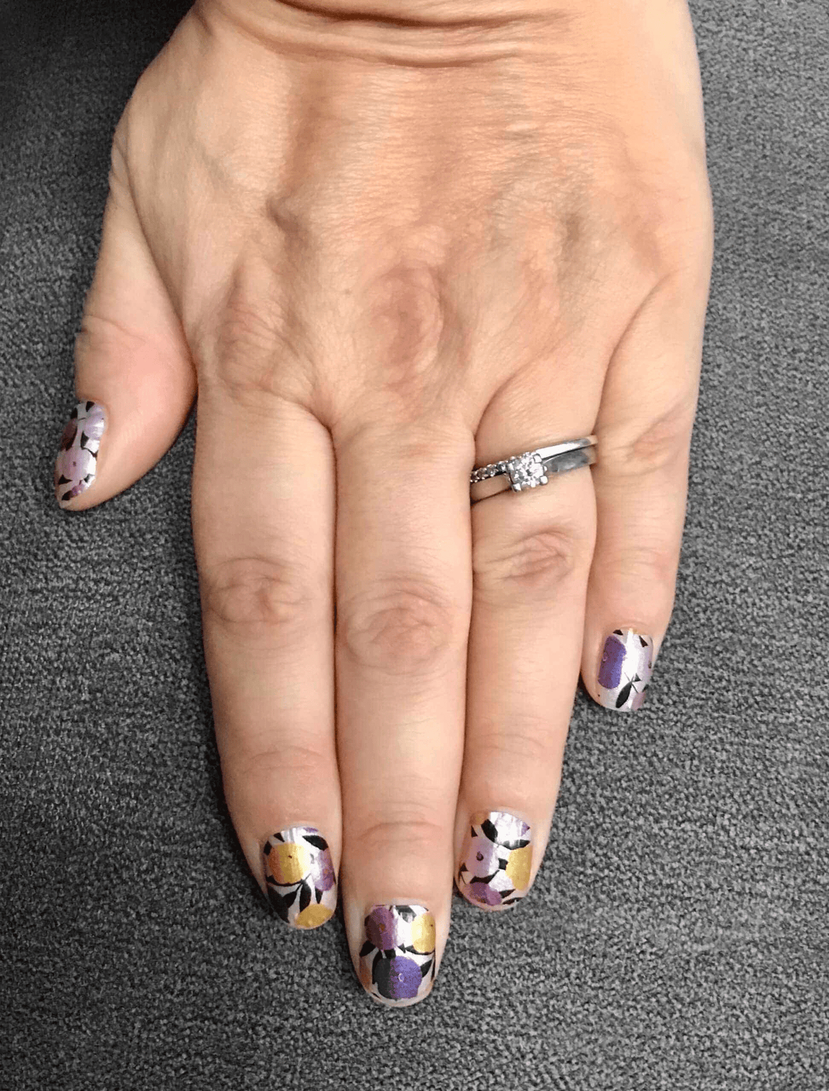 Purple and yellow daisy floral pattern nail wraps on hand for at-home manicure