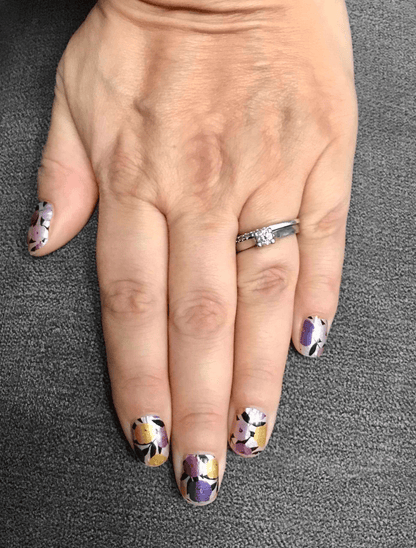 Purple and yellow daisy floral pattern nail wraps on hand for at-home manicure