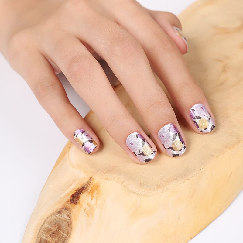 Purple floral nail art wraps applied on natural nails showing detailed flower design