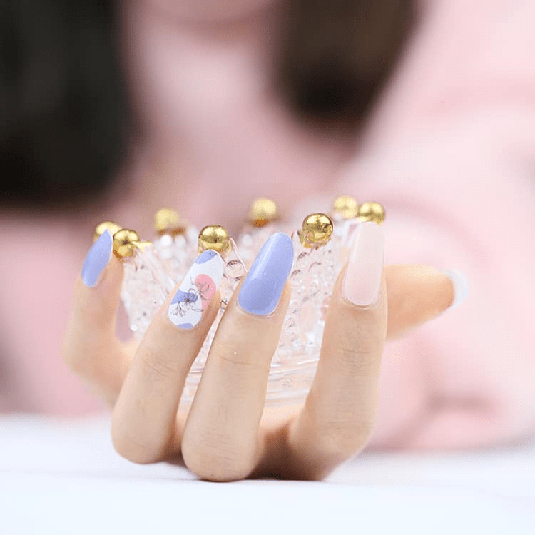 Blue floral nail wraps on hand featuring pink bergamot pattern for classic manicure