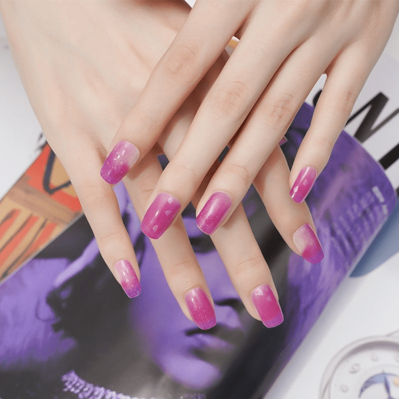Hand displaying purple gradient glitter nail wraps with geometric nail art design