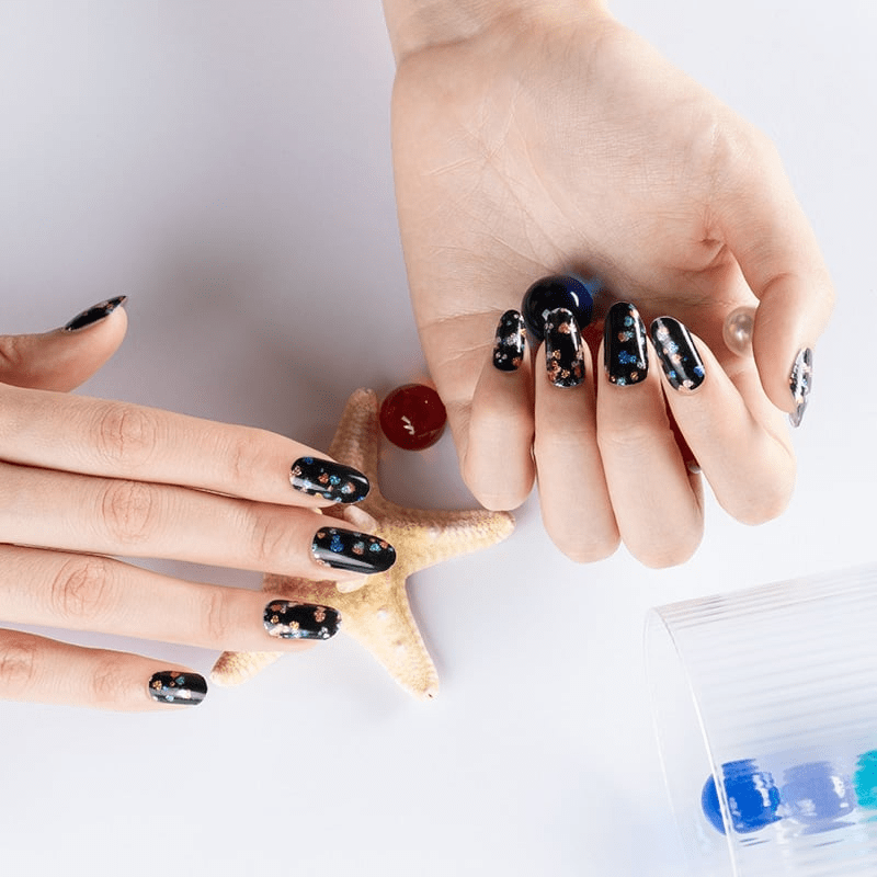 Black nail wraps with multicoloured glitter speckles, glossy finish on almond-shaped nails